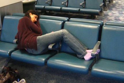 Moça tentando dormir nos bancos de um aeroporto no Egito